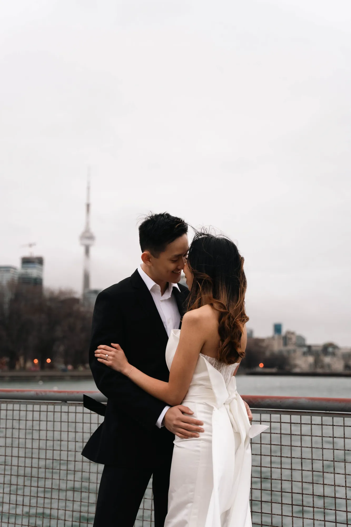 Groom embracing the bride on the Toronto waterfront with the CN Tower in the background